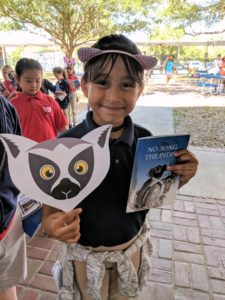 Student holds lemur mask and 'No Song the Indri' children's book