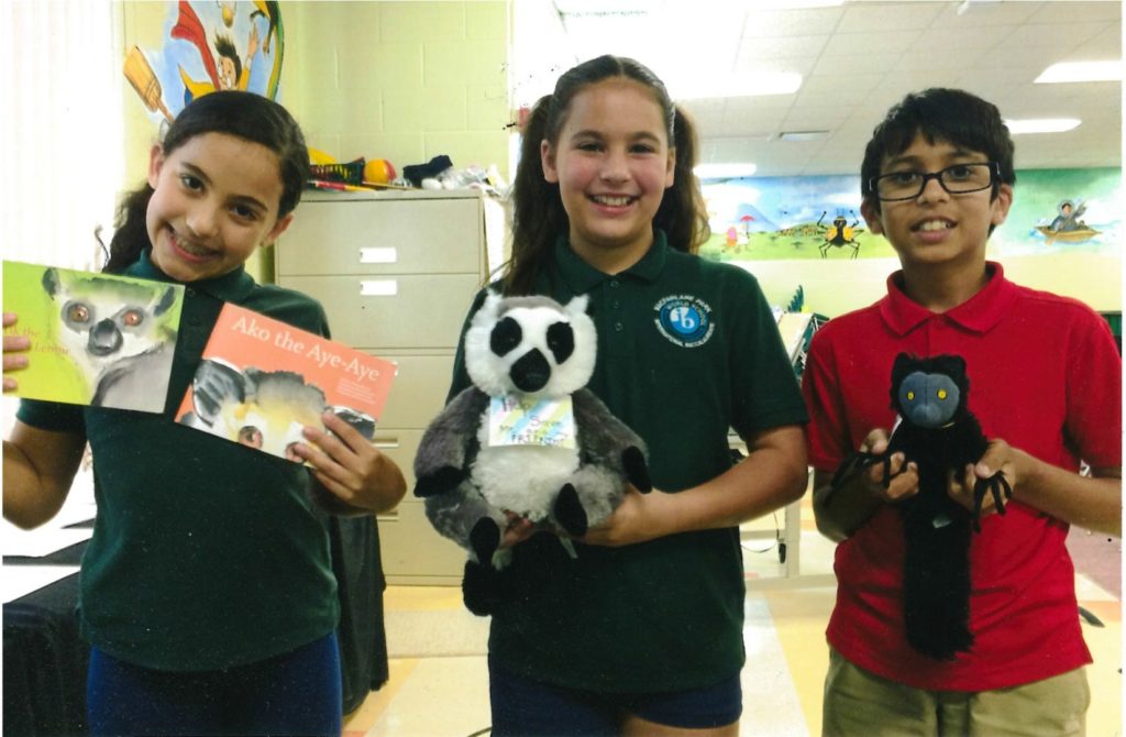 Students Isa, Aaliya, and Dev from MacFarlane Park School hold lemur items