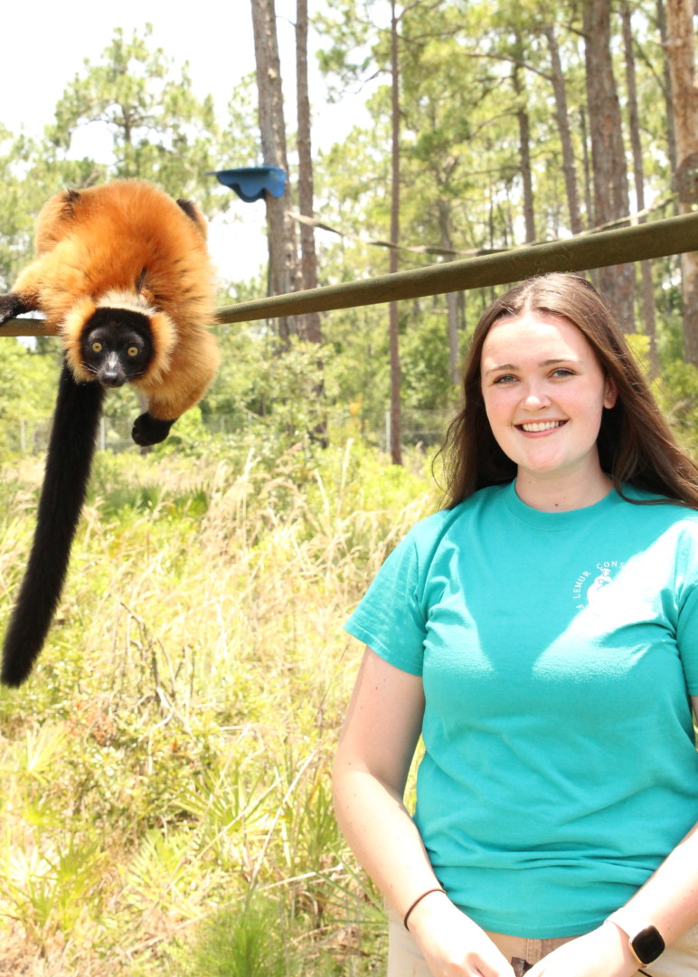 Shannon Frank Keeper Shannon Frank poses in free range forest with lemur in background